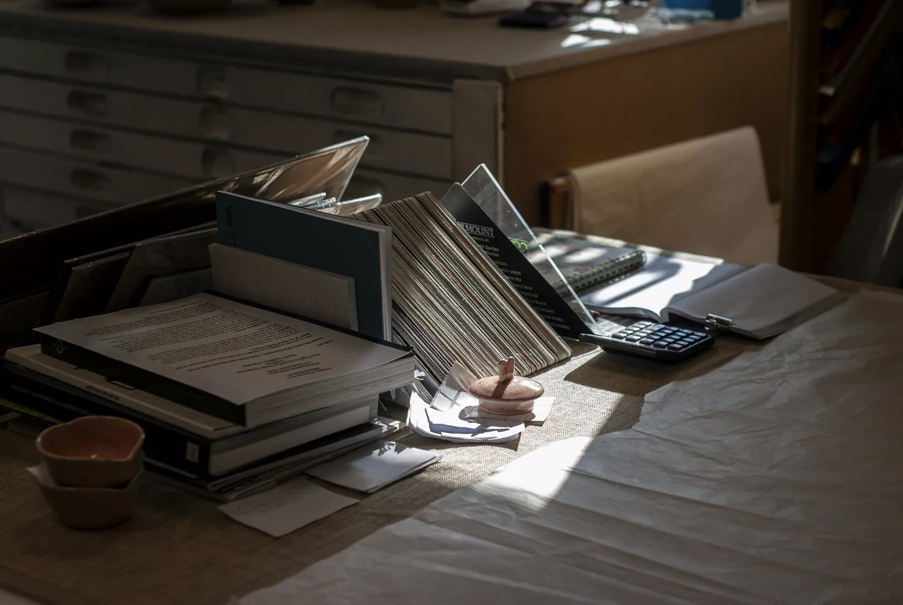 Files, documents and a calculator on a desk, in daylight.